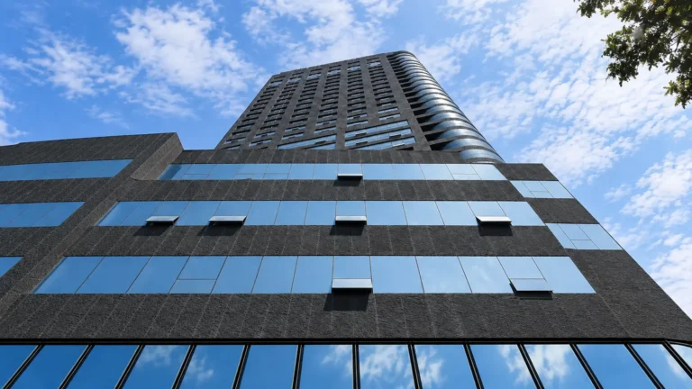 Dark textured exterior cladding on a modern high-rise building with reflective glass windows