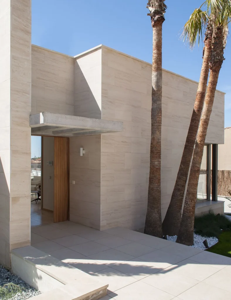 Beige travertine veneer on a modern villa entrance with palm trees