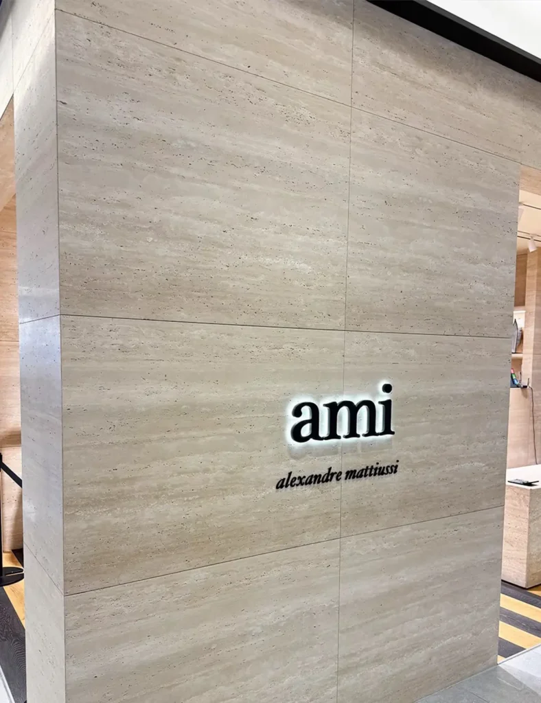 Beige travertine veneer feature wall with illuminated brand signage in a commercial interior