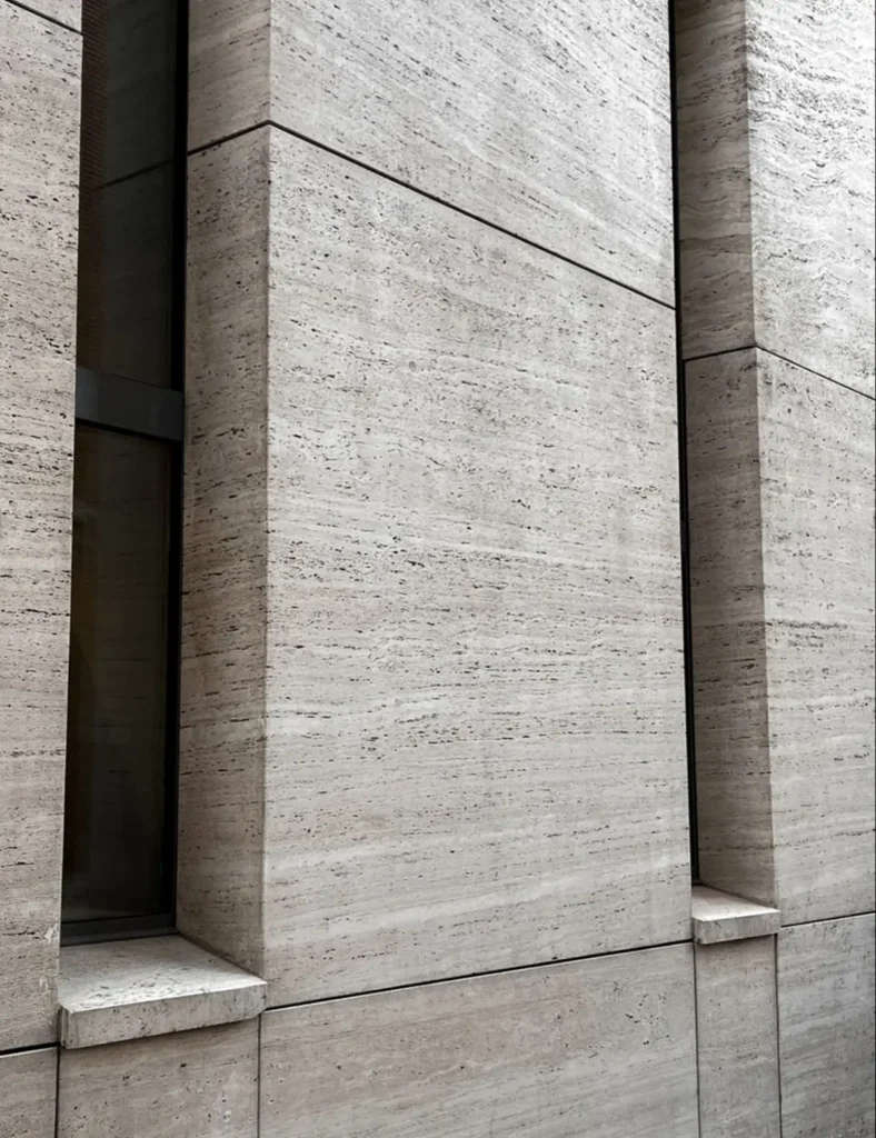 Gray travertine veneer facade with recessed windows and aligned panel joints