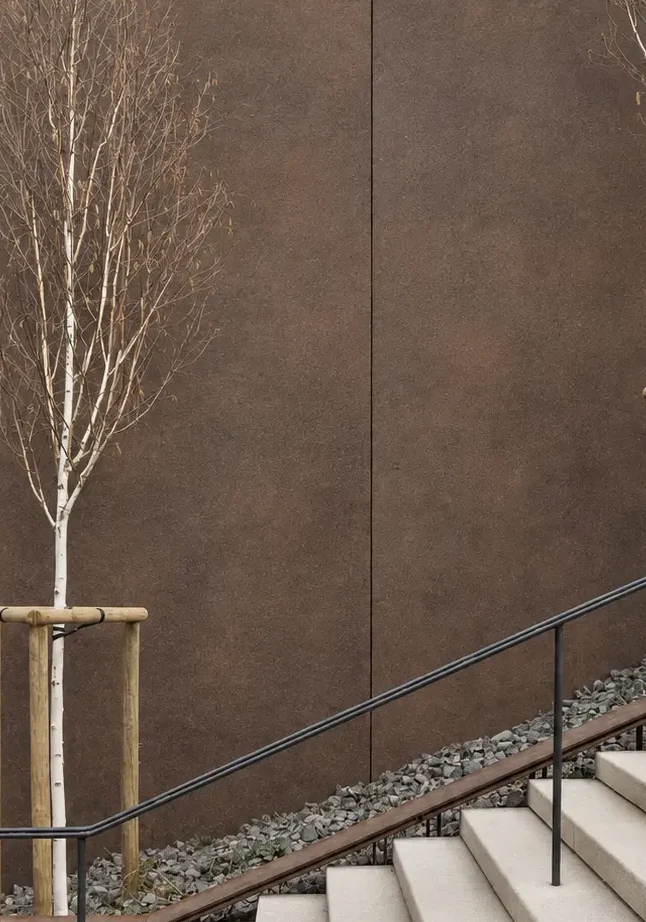 Aged Bronze Antique Patina flexible stone panels used as exterior wall cladding beside architectural stairs