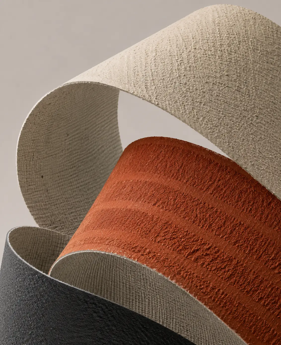 Curved flexible stone panels in beige, terracotta and charcoal finishes showing their bending ability