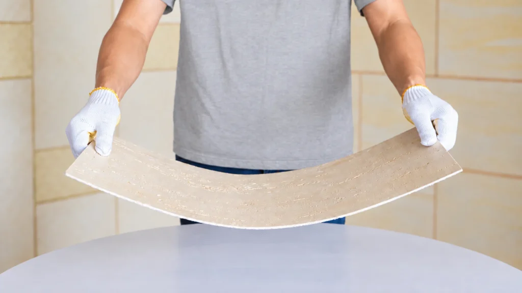 Worker bending a flexible stone sheet to demonstrate its flexibility