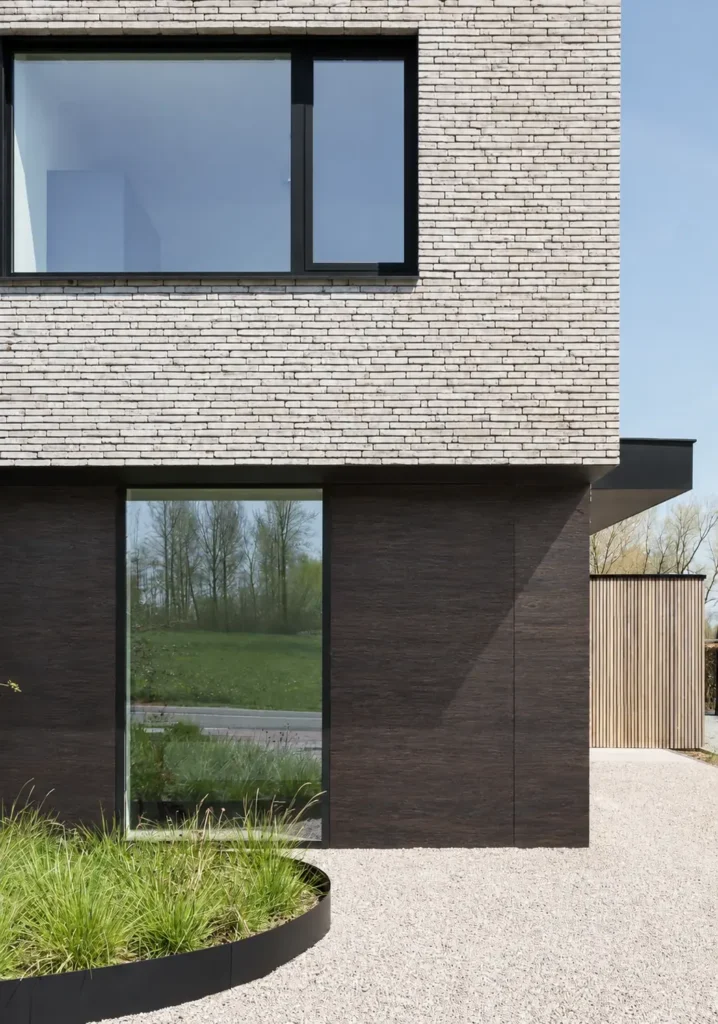 Dark smoked oak flexible stone cladding on the lower facade of a contemporary residence