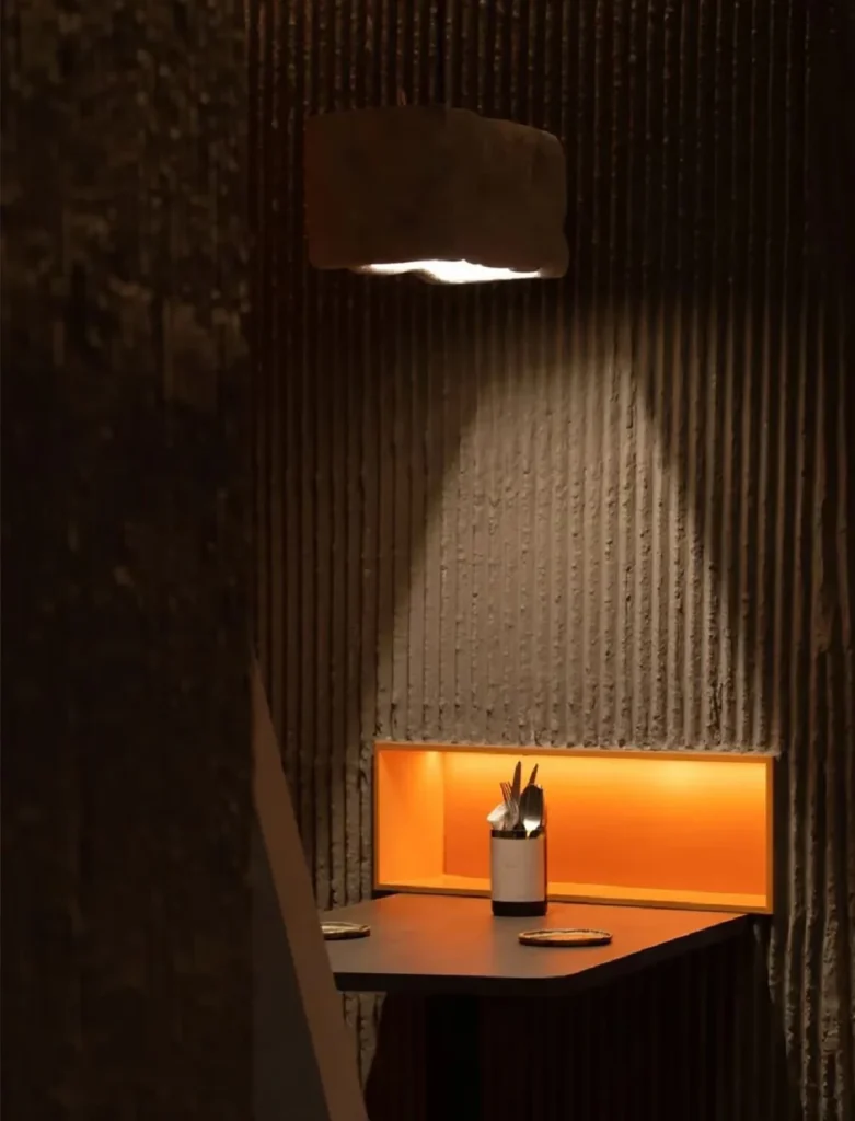 Exterior facade of Wine Nuts restaurant and wine bar in Singapore, clad with vein stone textured MCM flexible stone veneer under warm night lighting