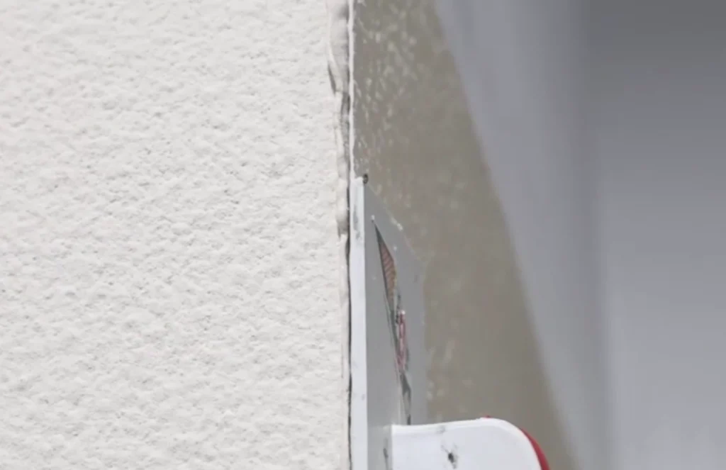 Close-up of a 45-degree outside corner joint being compacted so the sealant fully fills the inside corner space of the flexible stone installation.