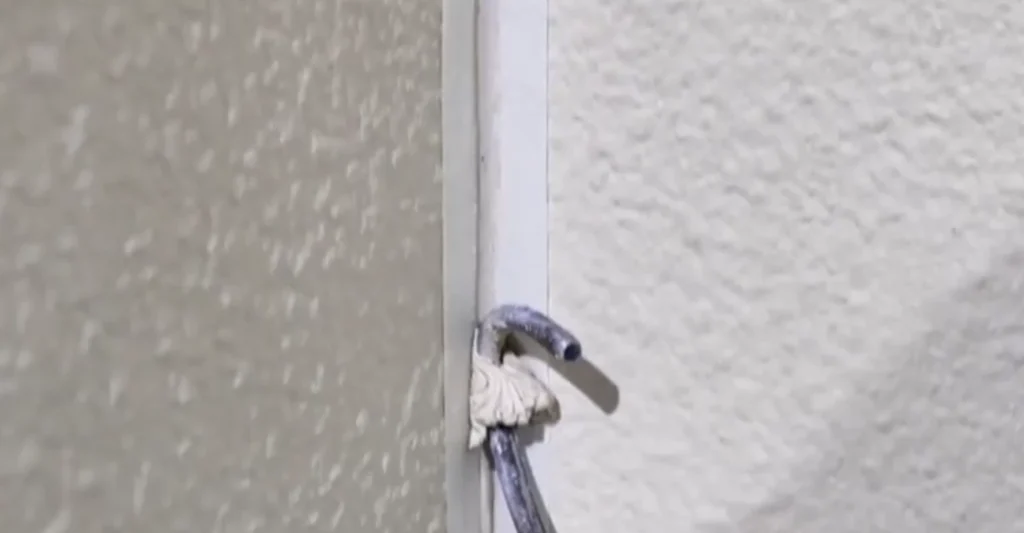 Installer using a jointing tool to compact and shape the sealant in a flexible stone internal corner.