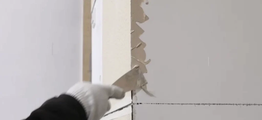 Worker applying weather-resistant sealant along the outside corner gap between flexible stone and the wall substrate.